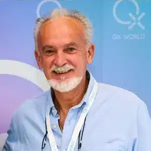 Homme âgé souriant avec une barbe blanche lors d'une conférence